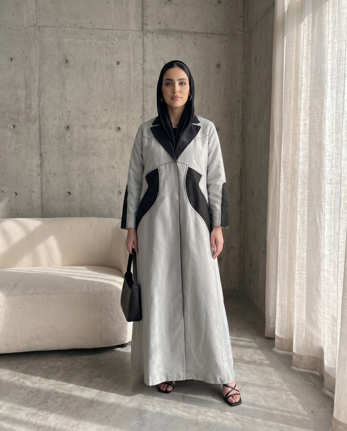 عباية ذات تصميم هيكلي بلونين، فضية اللون، مزينة بتطريزات هندسية فحمية اللون.