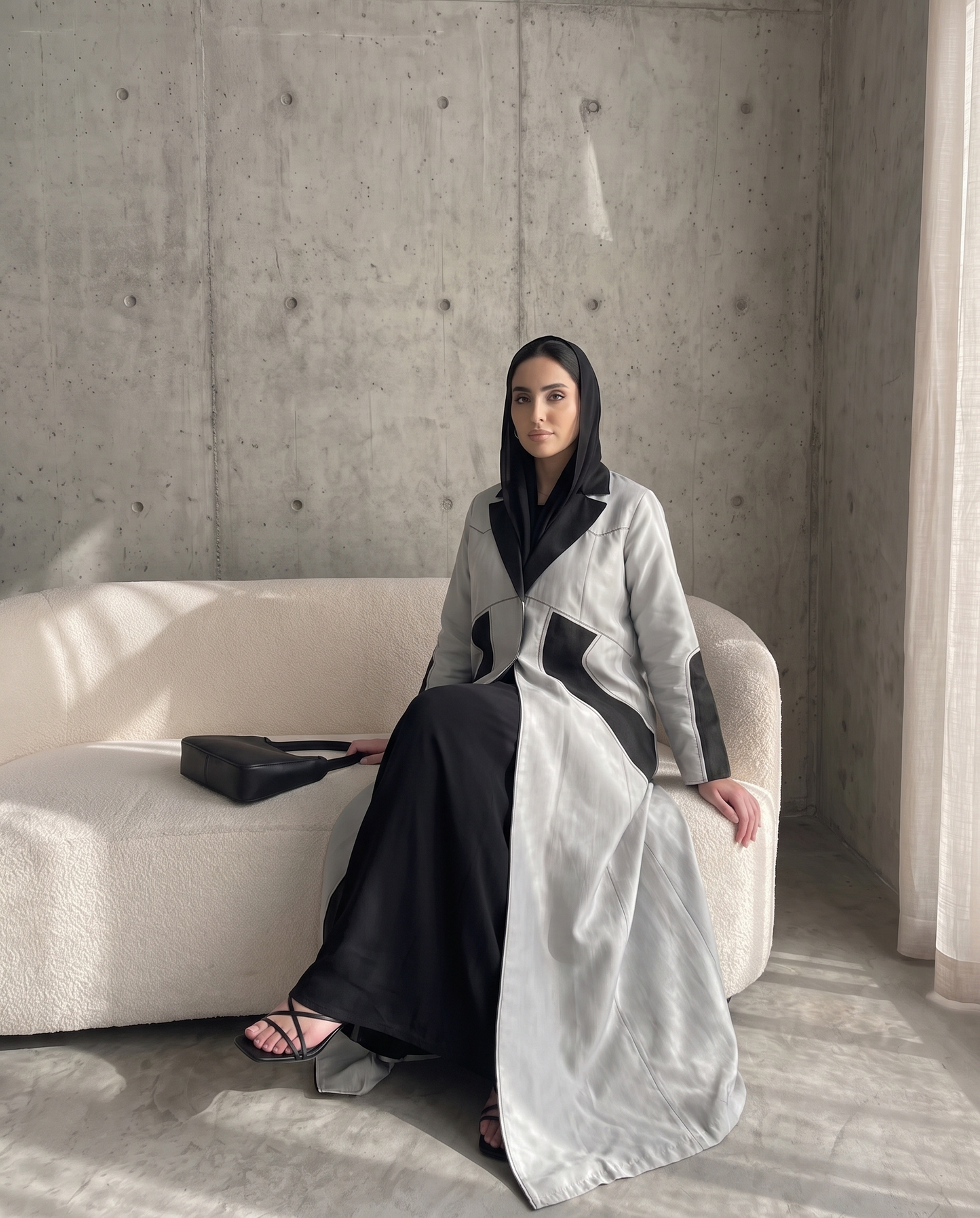 عباية ذات تصميم هيكلي بلونين، فضية اللون، مزينة بتطريزات هندسية فحمية اللون.