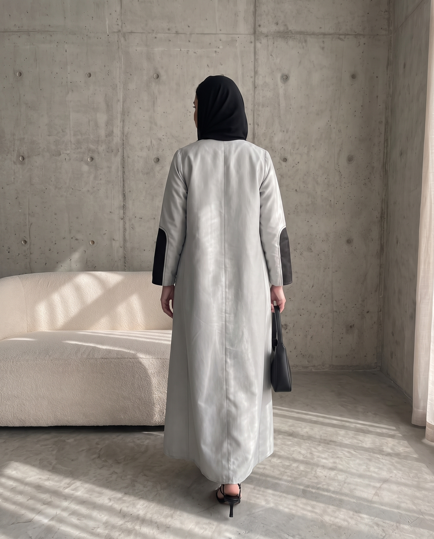 عباية ذات تصميم هيكلي بلونين، فضية اللون، مزينة بتطريزات هندسية فحمية اللون.
