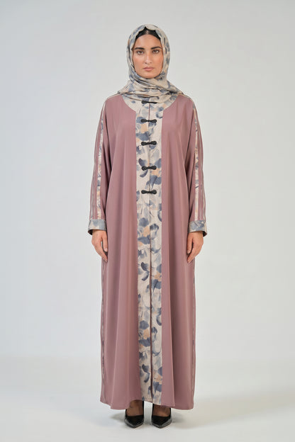 Woman wearing a long, light brown dress with floral patterns and a matching hijab on a white background